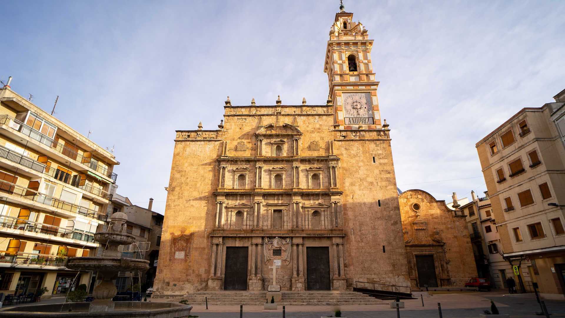 Iglesia de Chelva, con su fachada histórica y campanario en una plaza del pueblo.